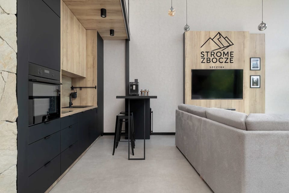 A bright living room with wooden accents and large windows. The apartment has a modern and welcoming atmosphere.