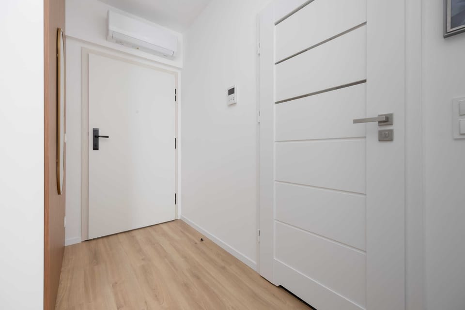 Minimalist hallway with wooden flooring and white interior doors