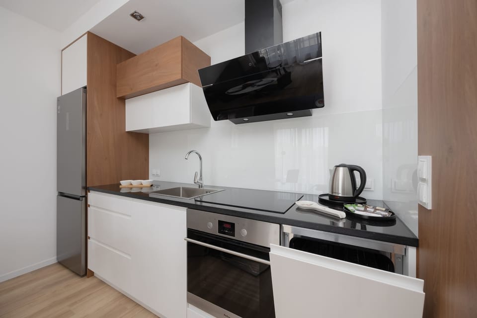 Contemporary kitchenette with black hood and wooden cabinets