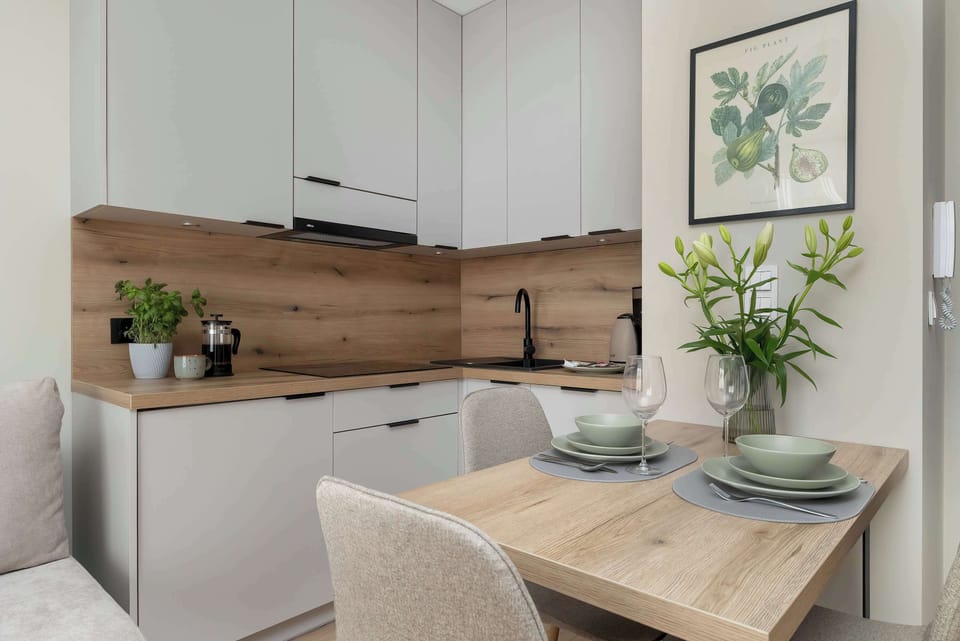 A contemporary kitchen and living space with sleek cabinetry and integrated appliances. The design emphasizes practicality while maintaining a warm aesthetic.