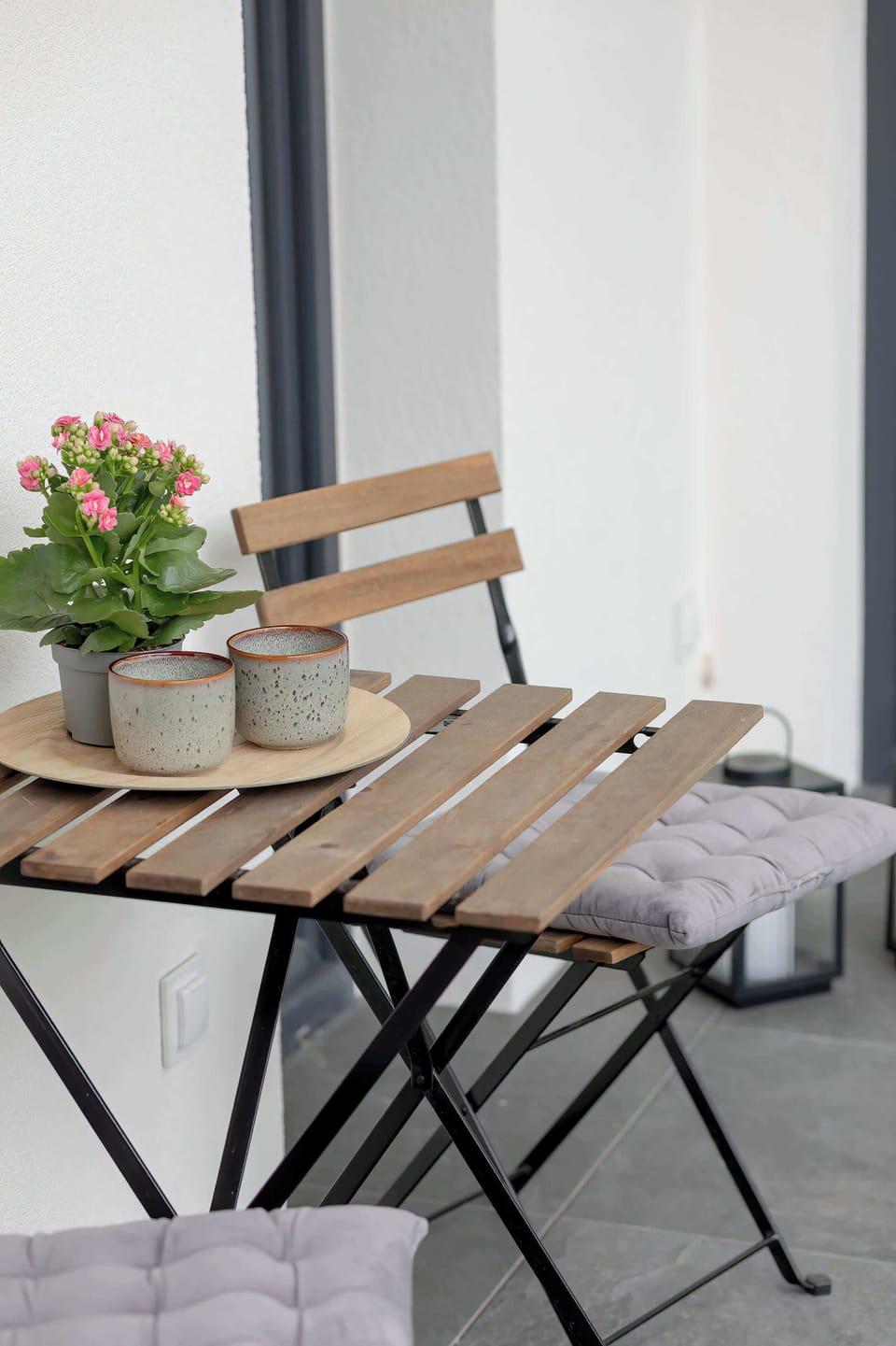 A small outdoor balcony setup with a table and seating. It provides a comfortable spot for coffee or relaxation.