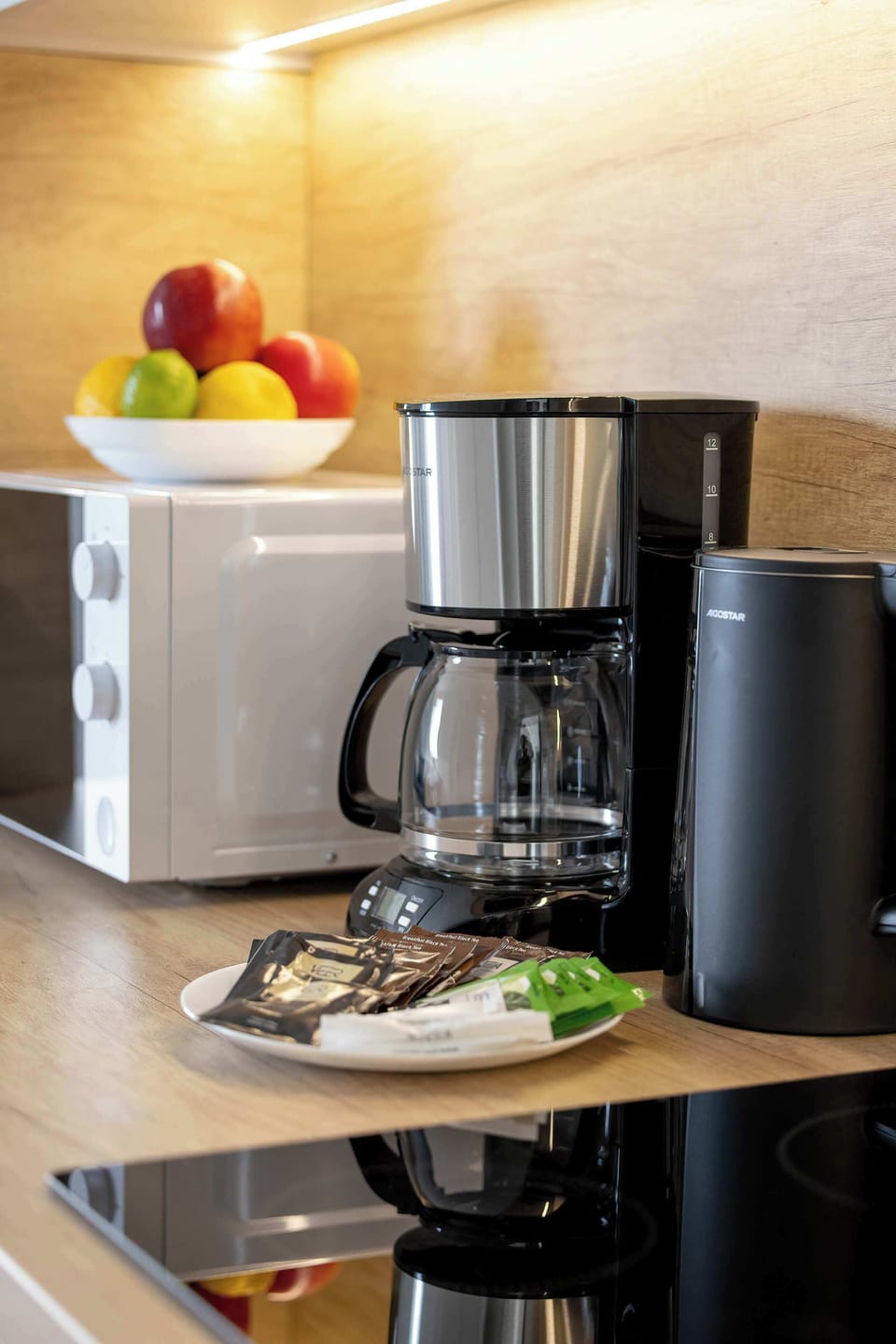 A vertical close-up shot focuses on a black drip coffee maker and a white microwave oven on the kitchen counter. 