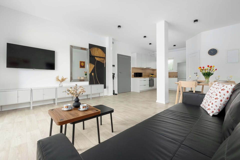 A modern living area with a black sofa and wooden coffee table. The apartment has an open and comfortable layout.