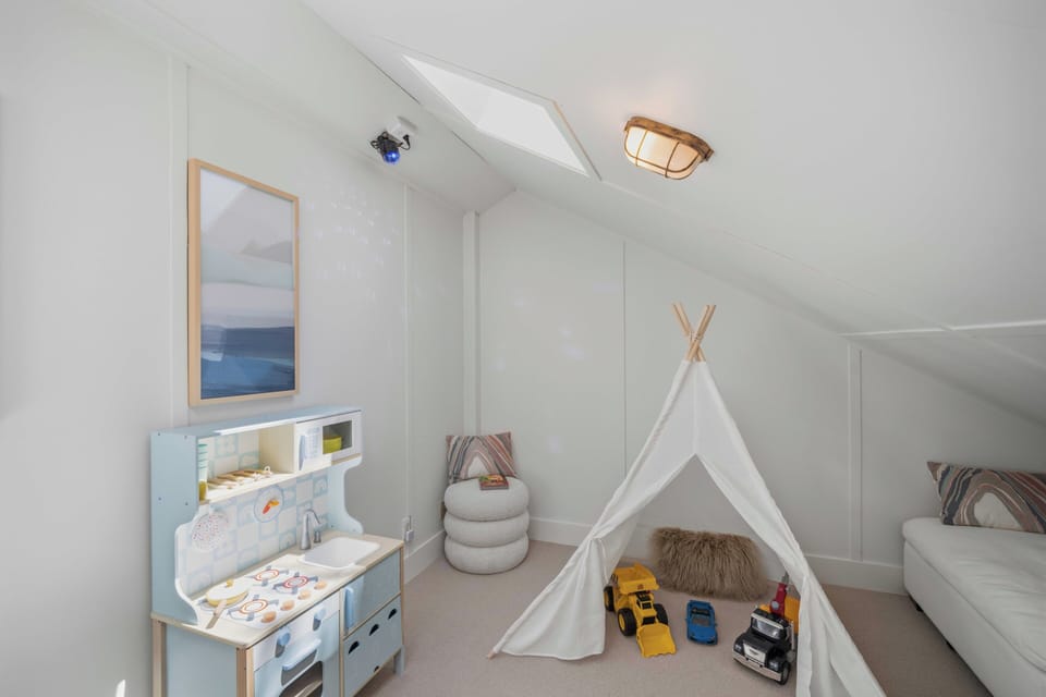 A charming hideaway where little adventurers can let imaginations soar—your kids will love this cozy play space tucked beneath pitched ceilings with toys and soft seating waiting.
