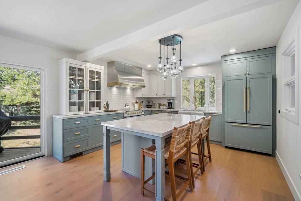 Your gourmet kitchen awaits with elegant blue cabinetry, gleaming marble countertops, and custom lighting—perfect for preparing memorable meals together.