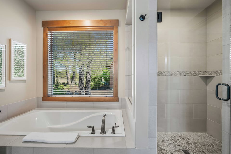 Unwind in your private spa-like bathroom with a soaking tub overlooking lush greenery and a sleek walk-in shower. The perfect retreat after a day of exploring.