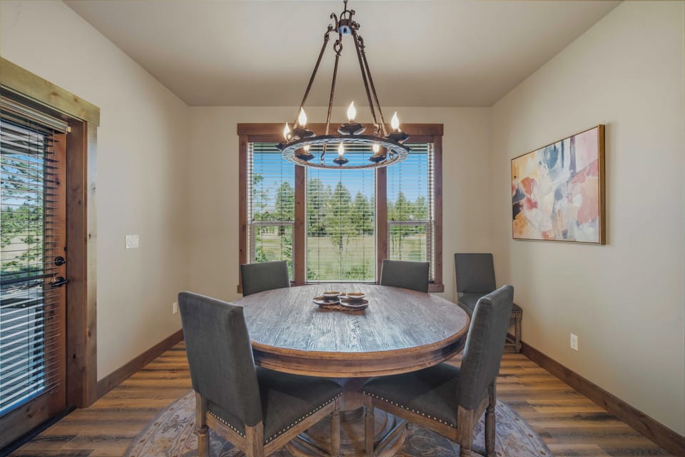 Gather around this inviting round table under rustic chandelier light, with mountain views framing your memorable meals together in this warm dining space.