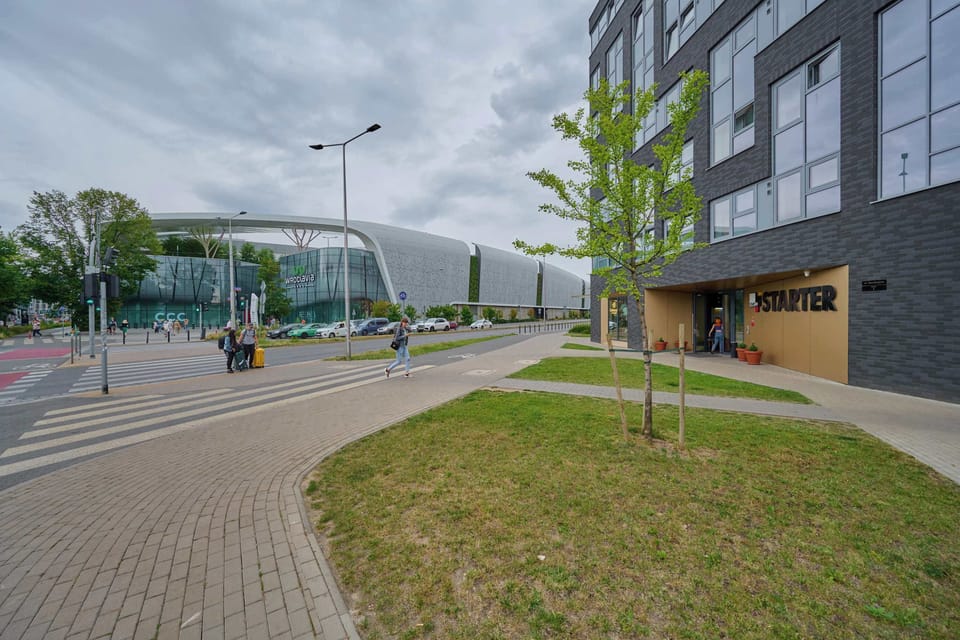 A pathway leading to the building, emphasizing its contemporary design and urban setting.


