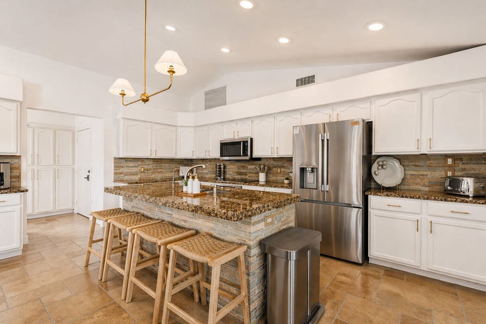 A bright, welcoming kitchen designed for gathering—featuring a spacious island with bar seating, warm finishes, and everything you need to cook, connect, and enjoy time together.
