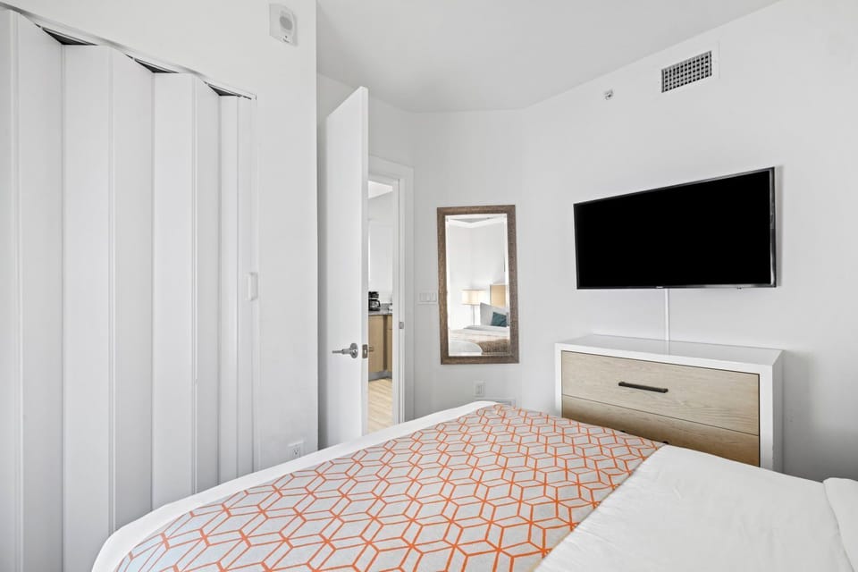 Relax in a cozy bedroom featuring a plush bed, contemporary decor, and a convenient TV for your entertainment.