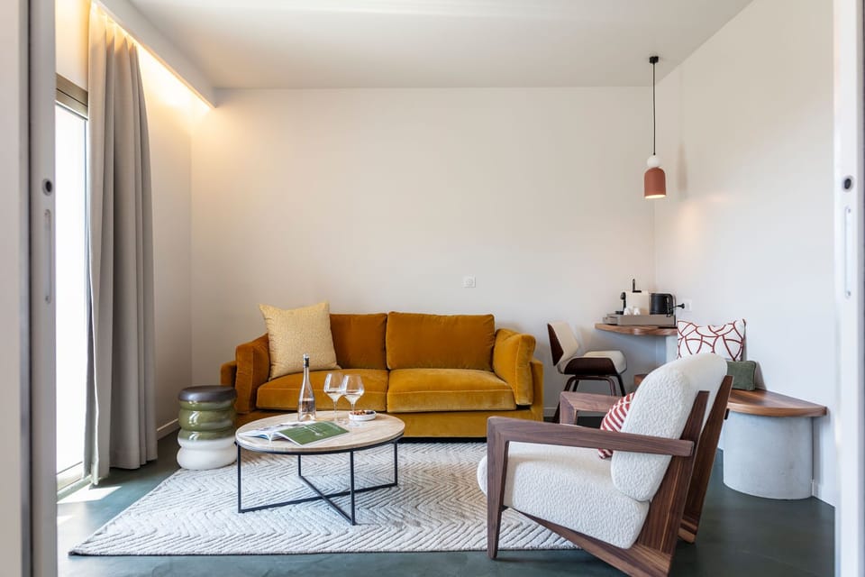 Mustard sofa and a dining area in the natural light of the suite's open-plan living space