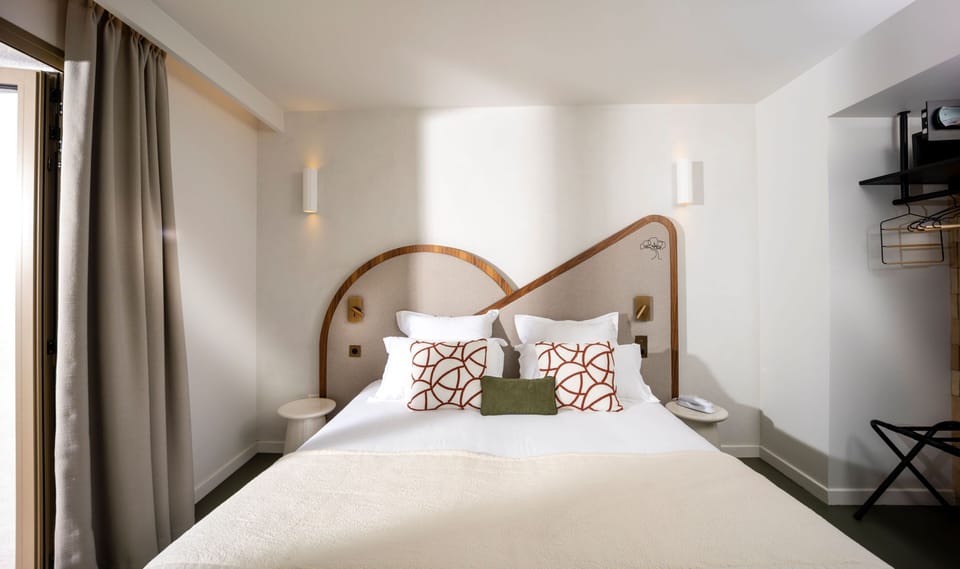 Cream bedding and a plush throw, with natural light streaming in from the terrace door