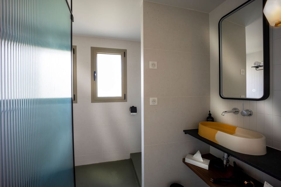 Glass shower and an orange round sink on a dark countertop in the en-suite bathroom