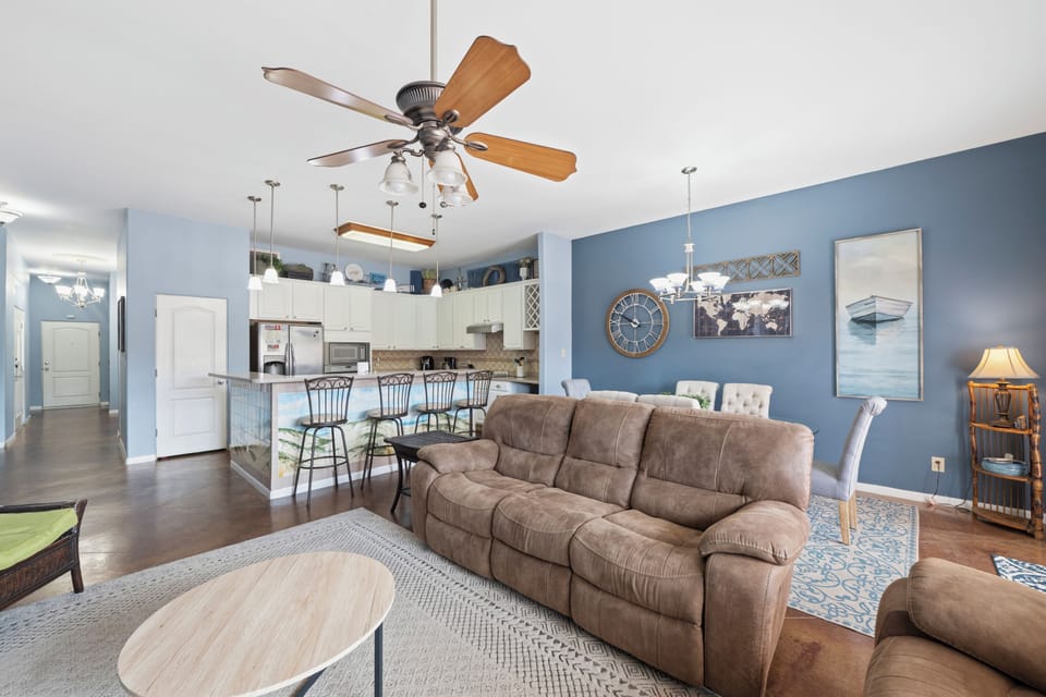 Picture yourself in this inviting open-plan retreat where coastal blues wrap around you. Sink into the plush sofa, feel the cool air from the ceiling fan, and savor meals at your breakfast bar overlooking everything.