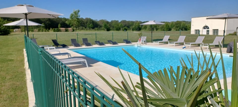 Turquoise outdoor pool with grey sun loungers and beige umbrellas — open from late May to mid-September