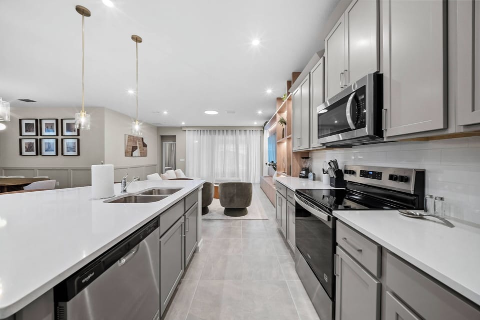 Experience a beautifully designed kitchen with sleek gray cabinetry and stunning white countertops, ideal for your culinary adventures.