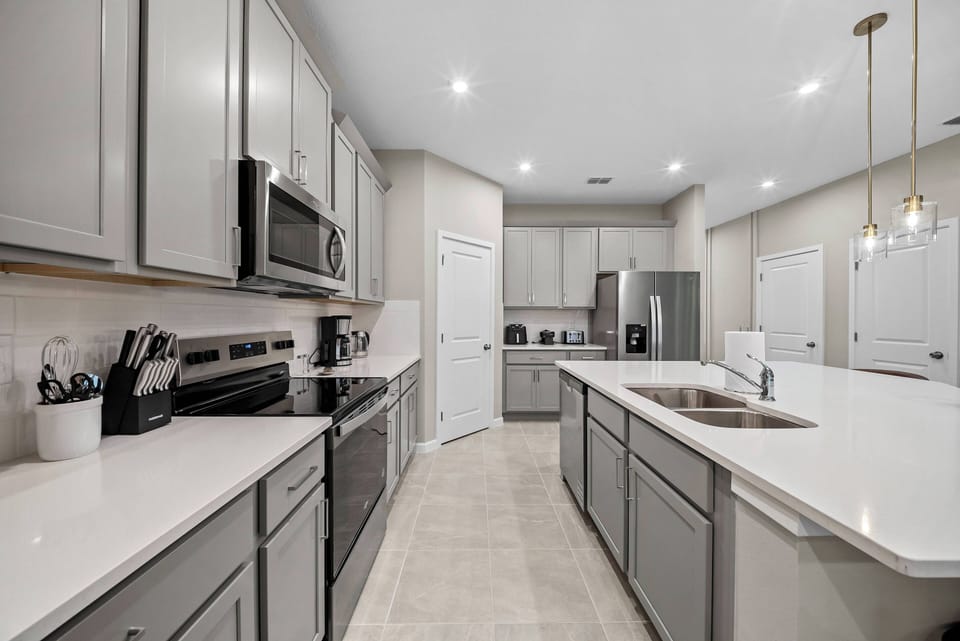 Enjoy a beautifully designed kitchen with sleek gray cabinetry and a spacious white countertop, perfect for culinary creativity. The warm lighting creates a cozy atmosphere, ideal for meals and gatherings with loved ones.