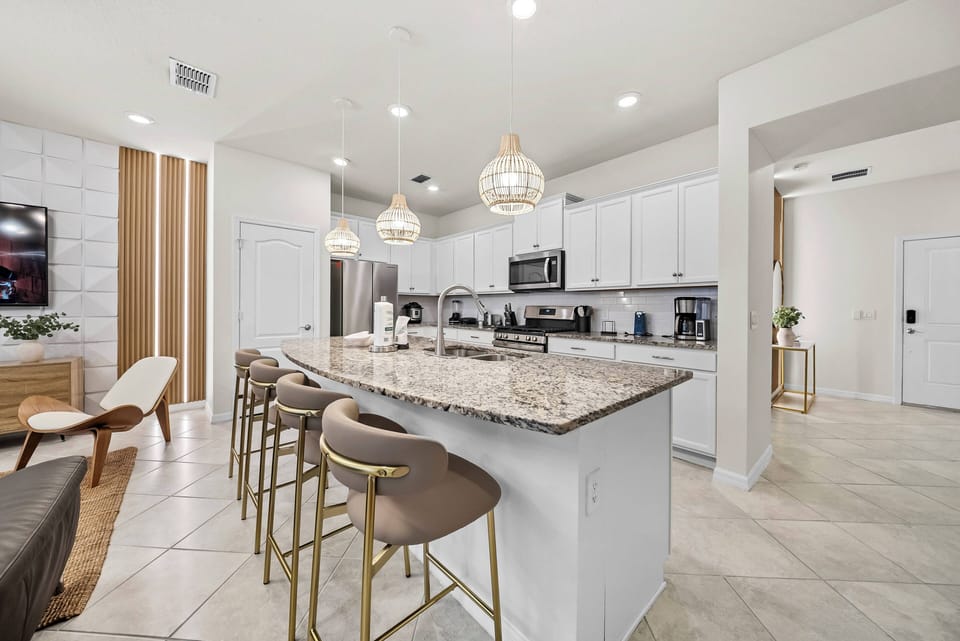 Discover a beautifully designed kitchen with sleek white cabinetry and a spacious granite-topped island. The warm wood accents and stylish pendant lighting make it a welcoming space for cooking and gathering with loved ones.