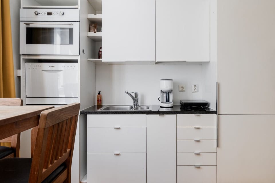 The modern kitchenette is fully equipped with a dishwasher and integrated appliances, making long-term stays or quick meals a breeze.