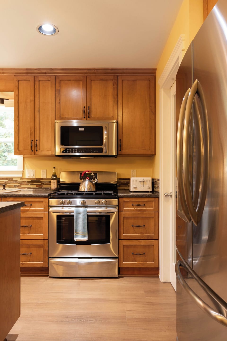 Warm full kitchen with stainless appliances and ample cabinet storage
