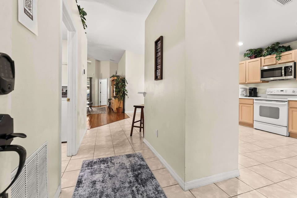 Entryway with tiled floors leading to a kitchen and living area with natural light.