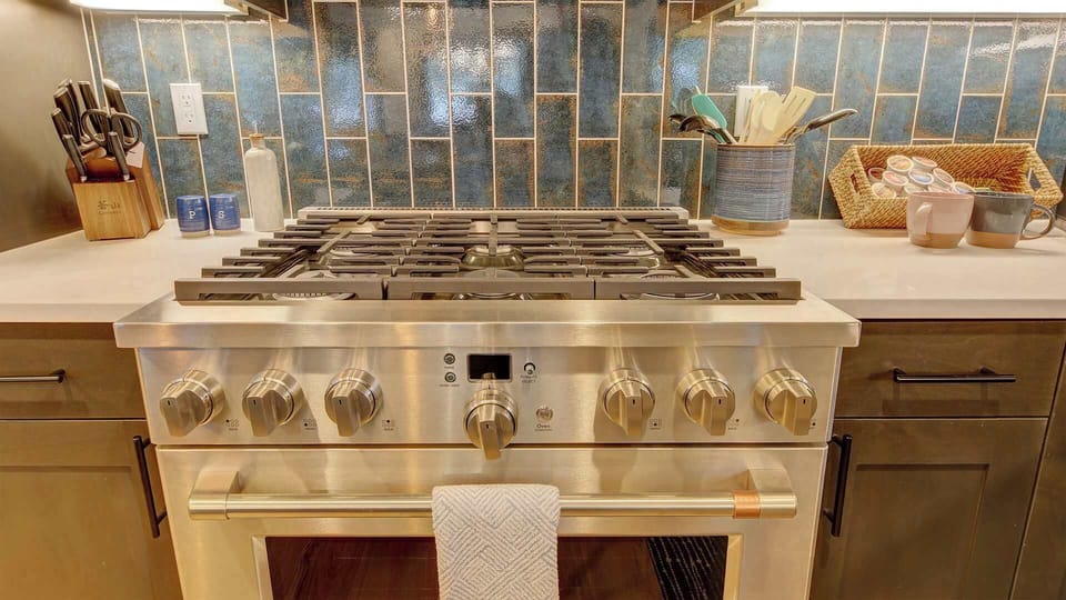 6-burner gas range and oven. Large assortment of cooking utensils, serve ware, pots, pans, stock pot, bakeware, and many other items.