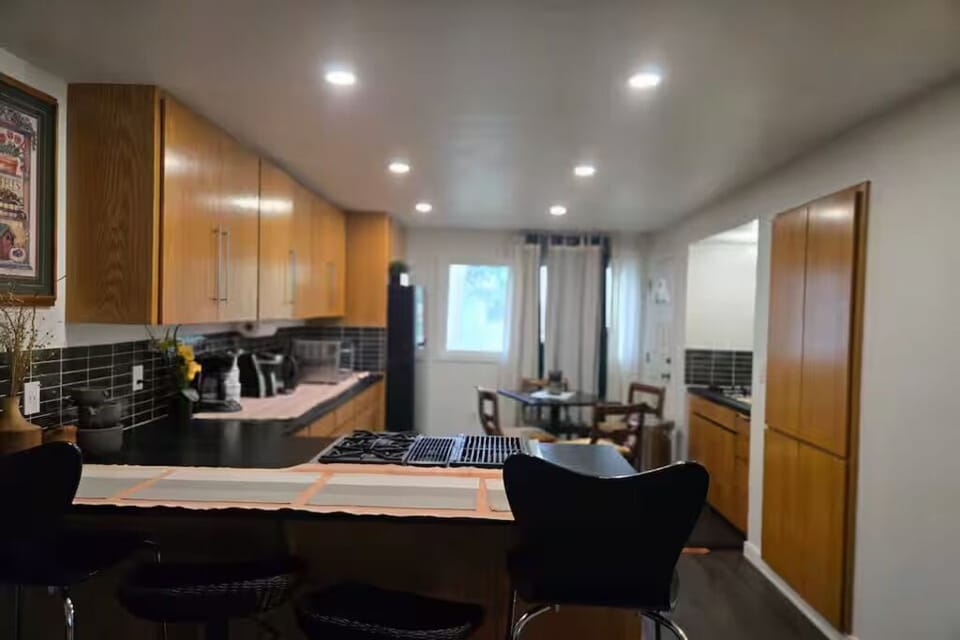 Enjoy a fully equipped kitchen with ample counter space, bar seating, and an adjacent dining area—perfect for cooking, gathering, and sharing meals together.