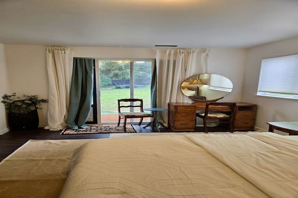 Spacious bedroom featuring a comfortable bed, dedicated vanity, ample storage, and large windows that fill the room with natural light. A peaceful retreat designed for rest and relaxation.