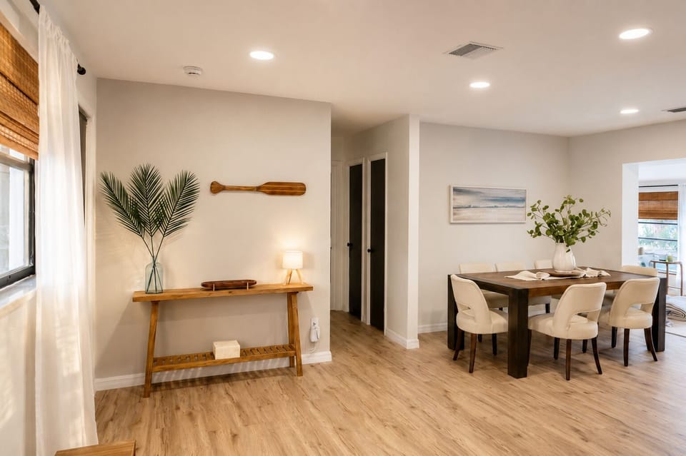 Long dining table for six in a bright, window-lined room
