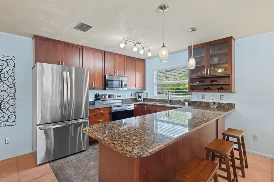Modern chef's kitchen featuring granite countertops, stainless steel appliances, and bar seating.
