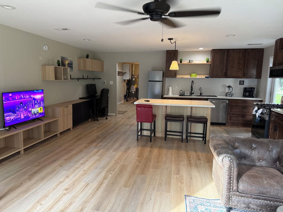 Bright open-concept living area with full kitchen, island seating, and workspace