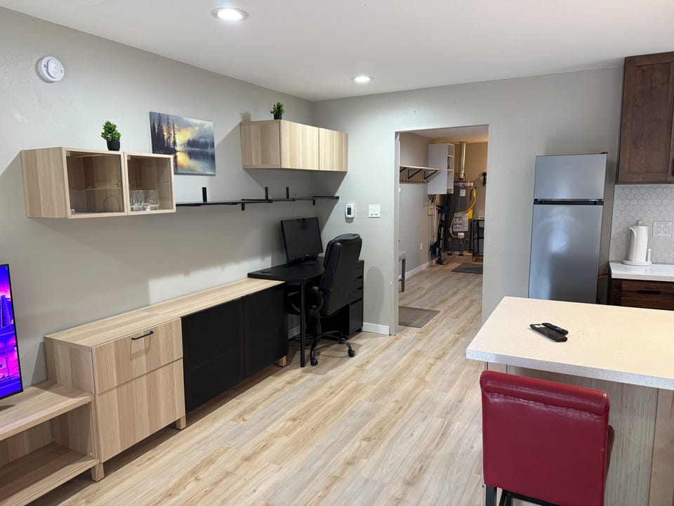Modern open living space with workspace, breakfast bar, and sleek kitchen