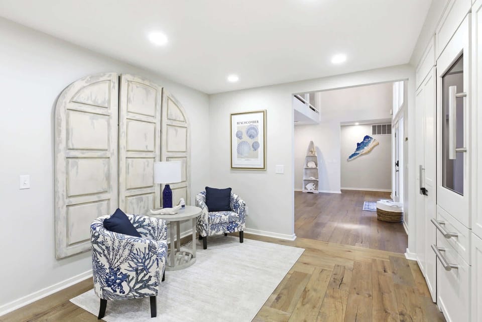 Distressed arched door wall panels, blue-and-white coral print armchairs, and shell print art create an artful, coastal-chic welcome the moment you step inside.