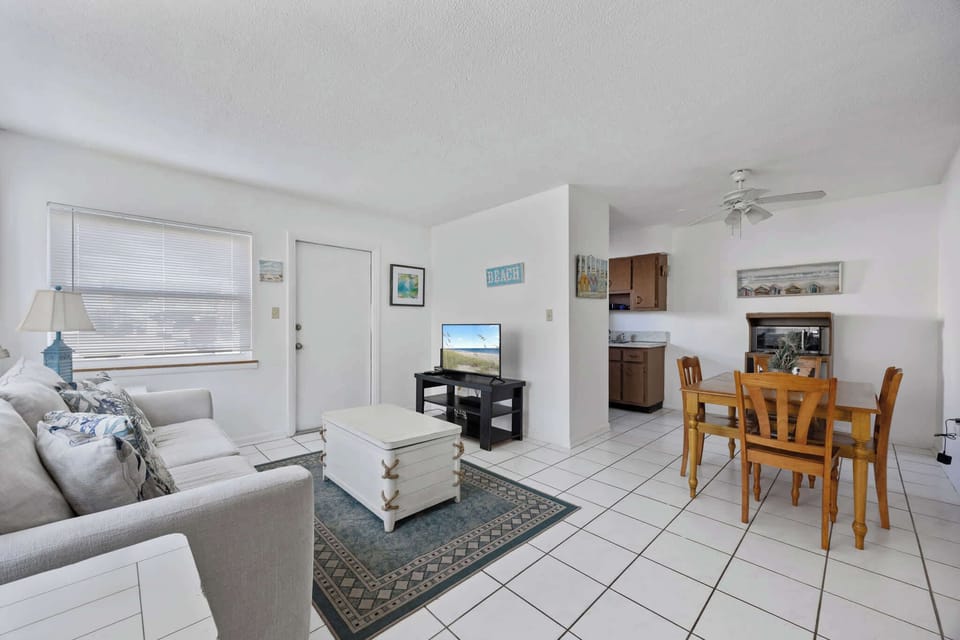 Bright living and dining area with coastal decor and tiled floors.