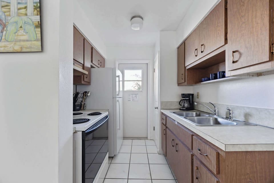 Compact kitchen with wooden cabinets and essential appliances for convenient cooking.