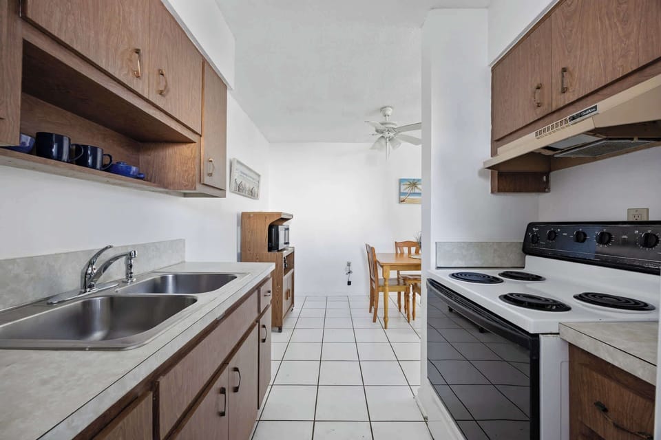 Compact kitchen with wooden cabinets and a dining area in the background