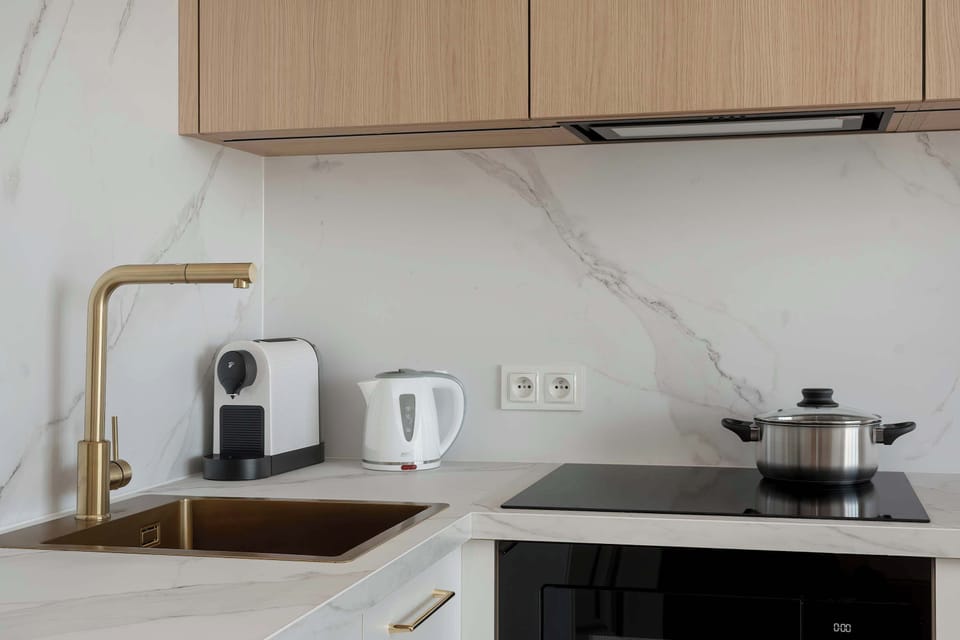 
A stylish kitchen counter with a stovetop, coffee machine, and minimalist wooden cabinets. Light colors add a modern touch to the interior.