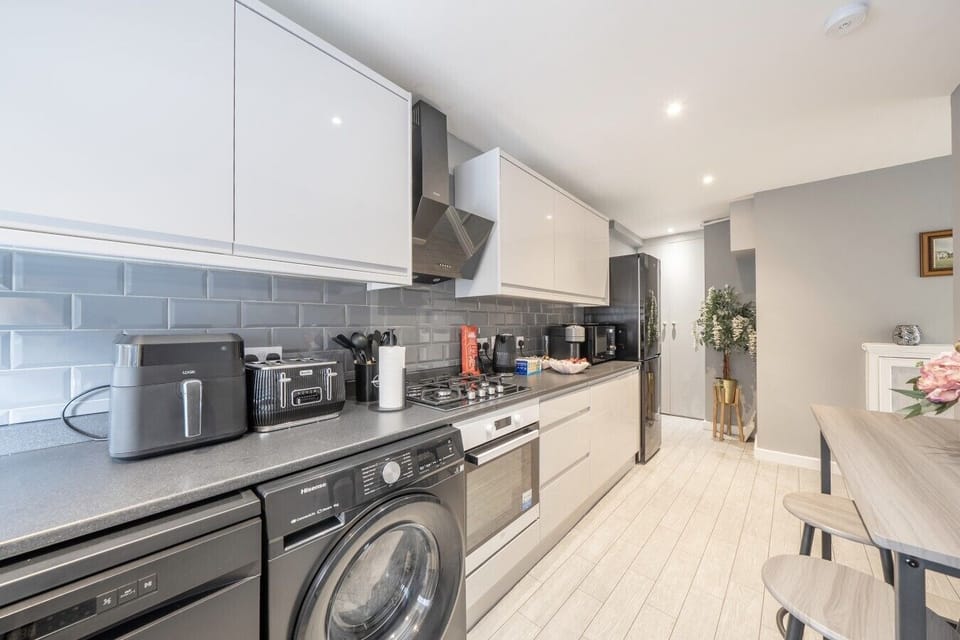 Well-equipped kitchen with washer, oven and coffee machine.