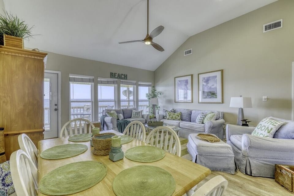 Unwind in your bright, airy living and dining space with vaulted ceilings, coastal decor, and stunning views of the water just beyond your private balcony.