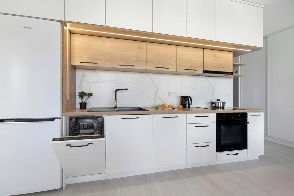 A spacious contemporary kitchen featuring white cabinets, wooden countertops, and modern appliances. The clean design combines simplicity with functionality.