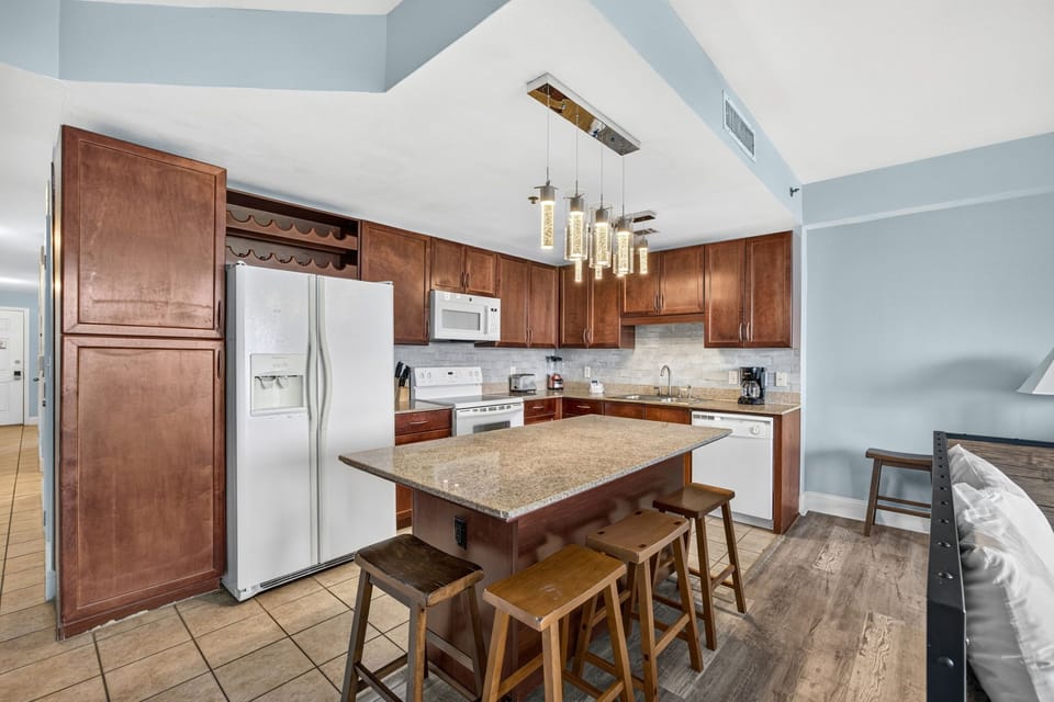 Your fully equipped kitchen features warm wood cabinetry, granite countertops, and a spacious island perfect for gathering with loved ones over morning coffee or evening meals.