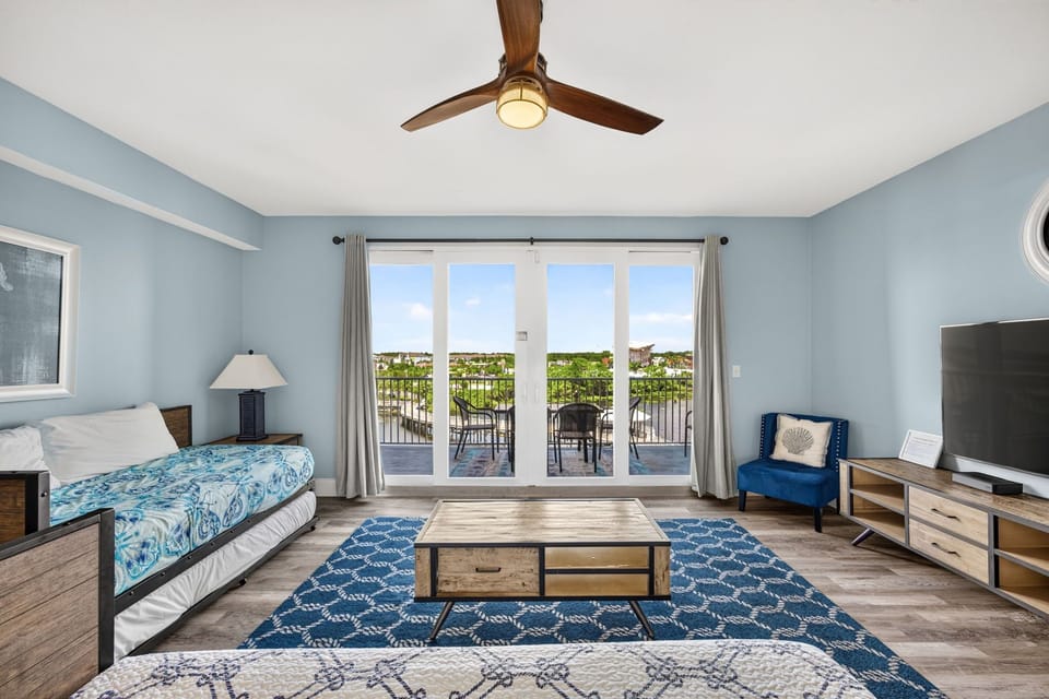 Sink into the coastal-blue calm of your suite, where glass doors frame your private balcony and gentle breezes drift through. Natural light fills the space as you unwind with scenic views just beyond.