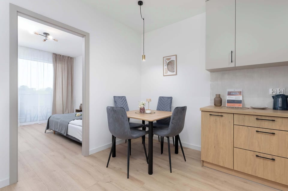 A modern dining table set placed within a bright kitchen area, creating a practical space for everyday meals. In the background, there are clean wooden cabinets and built-in kitchen appliances.