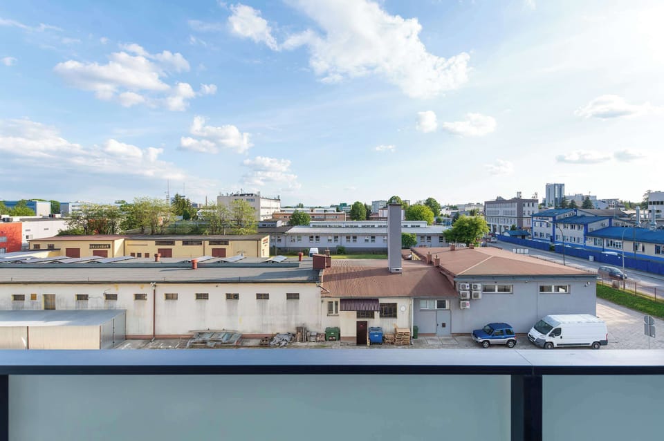 A balcony view overlooking surrounding city buildings and rooftops. The outdoor space offers fresh air and an urban perspective.