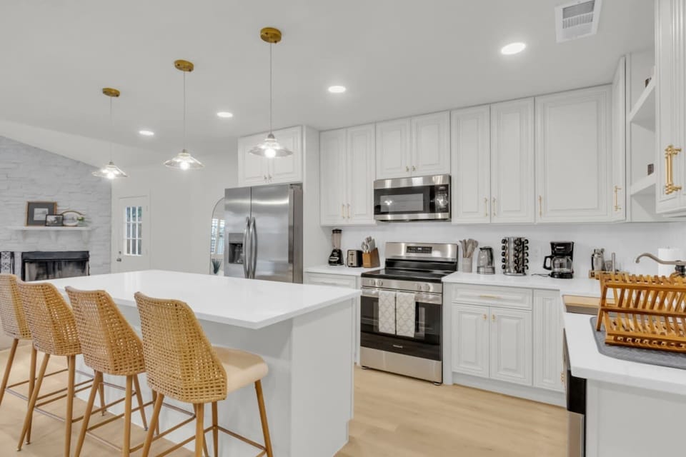 Bright kitchen with island seating for four, open shelving, dishwasher, microwave, and cooking basics. Perfect for guests who want a fully stocked setup while traveling.