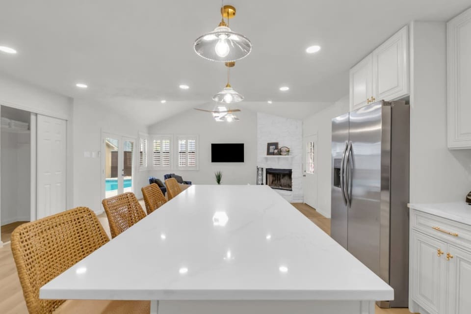 Oversized kitchen island with abundant prep space and bar seating, open layout connecting to the private living room and offering easy access to the backyard pool.