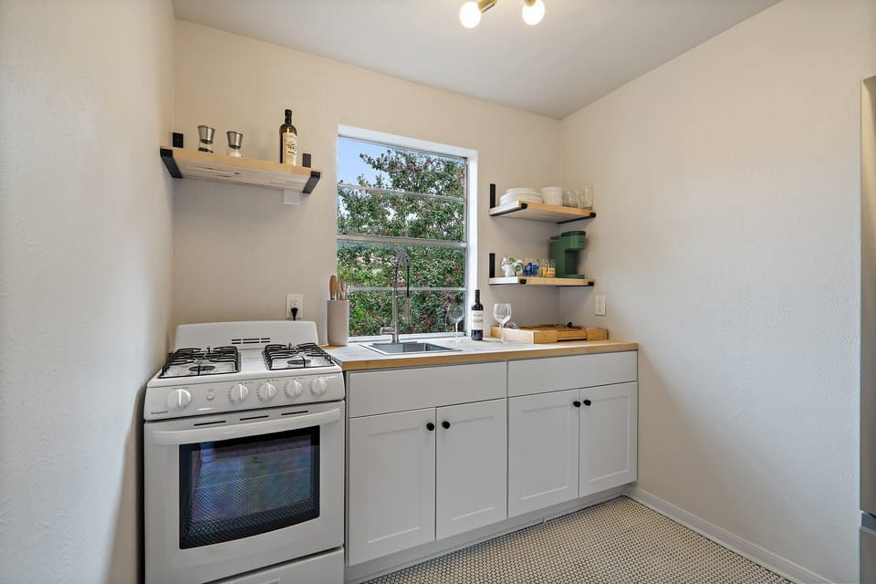 Detached Studio fully equipped kitchen with gas stove, white cabinetry, Keurig coffee maker, and cookware. Full set of dishes, silverware, cooking basics, and wine glasses provided.
