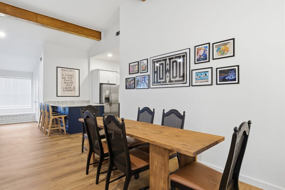 Dining table seats 8 with wood farmhouse table and black chairs. Open layout connects to fully stocked kitchen. Perfect for pregame group meals near AT&T Stadium.