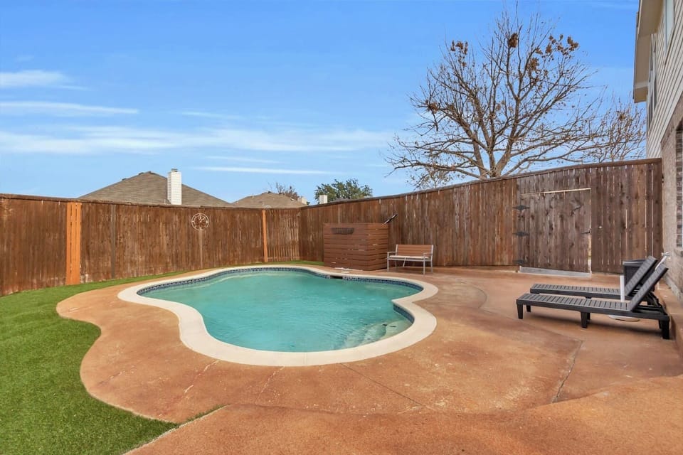 Enjoy a private outdoor pool located in a fully fenced backyard, with loungers and a bench perfect for relaxing, swimming, and spending time with your group.