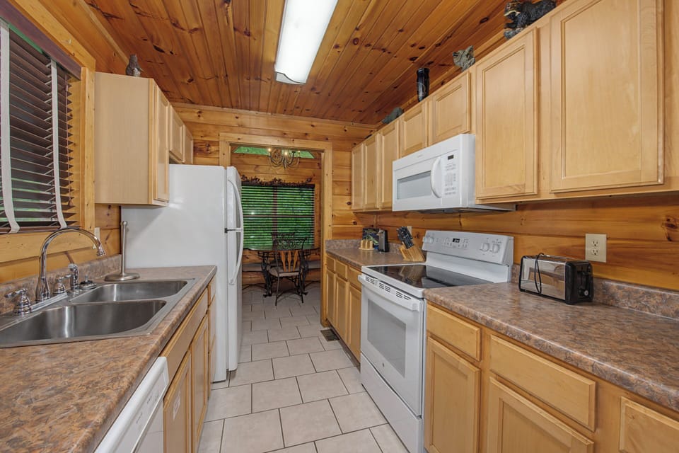 Your fully equipped kitchen awaits with stainless steel appliances, ample counter space, and warm wood finishes—perfect for preparing family meals and morning coffee in your mountain getaway.